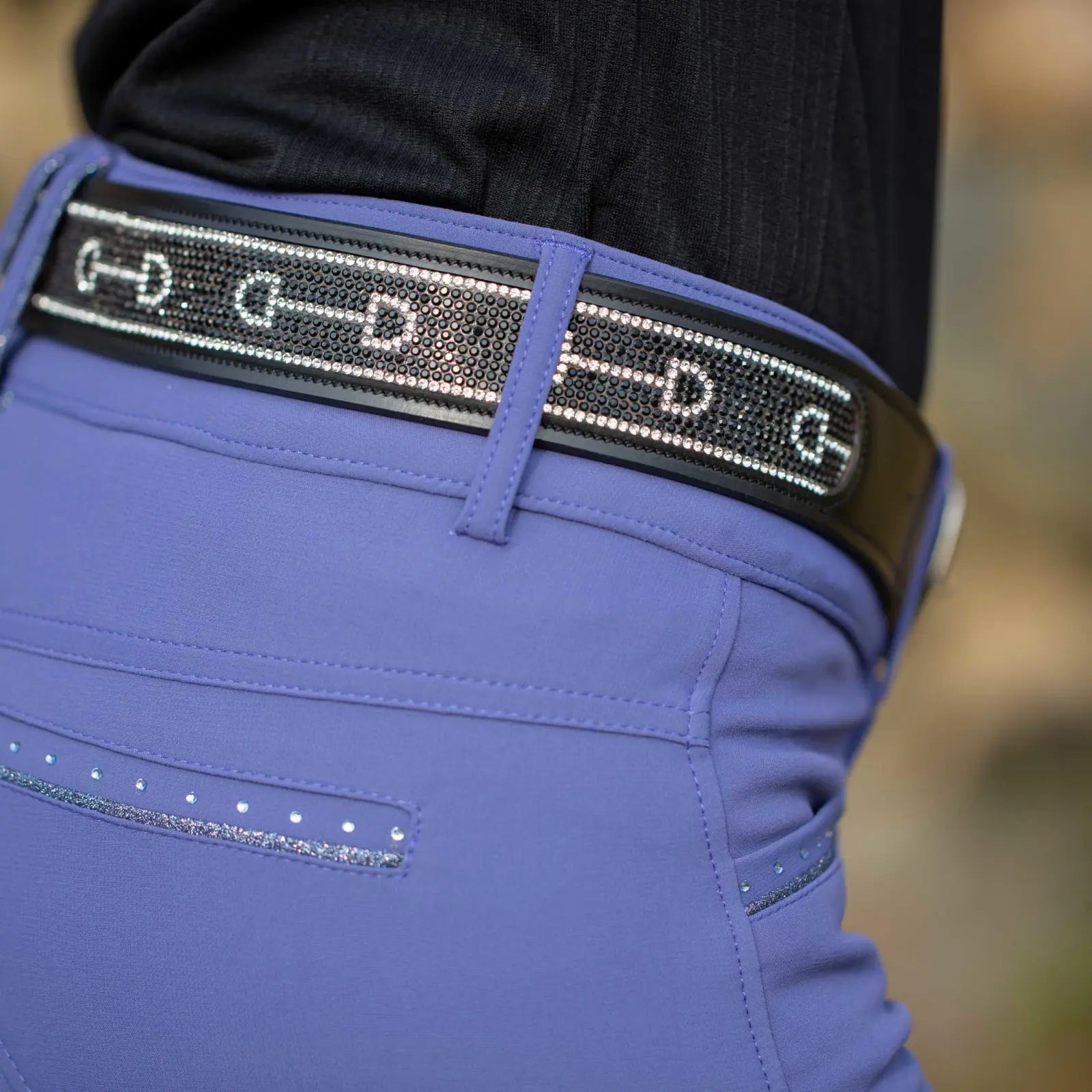 Close-up view of the black Equinavia Erika Crystal Bit Belt over blue breeches