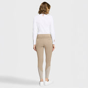 Full body back view of a female model wearing the sand Samshield Clara Premium Knee Grip Breeches and white shirts on a plain background