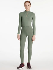 Full body front view of a young female model wearing the green Lemieux Young Rider Orla Pull On Tight and coordinating top on a white background