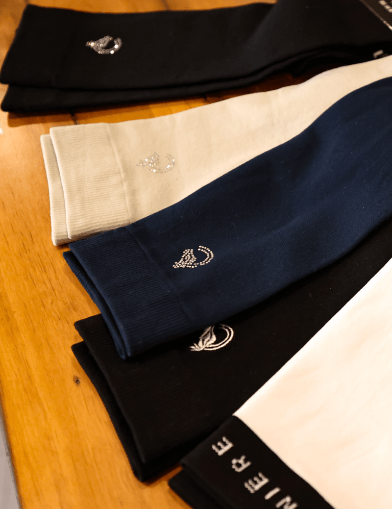 View of an assortment of colors of the Criniere Equestrian Socks lying on a wooden table