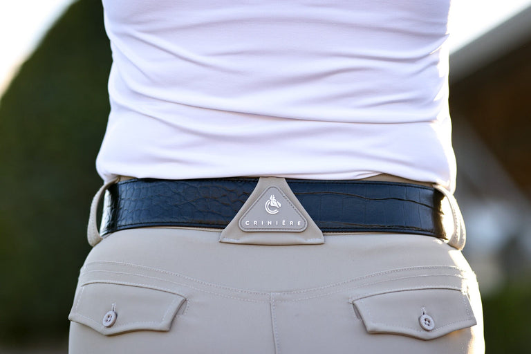 Close-up back view of a model wearing the black side of the Criniere Reversible Pebble Leather Logo Belt over tan breeches