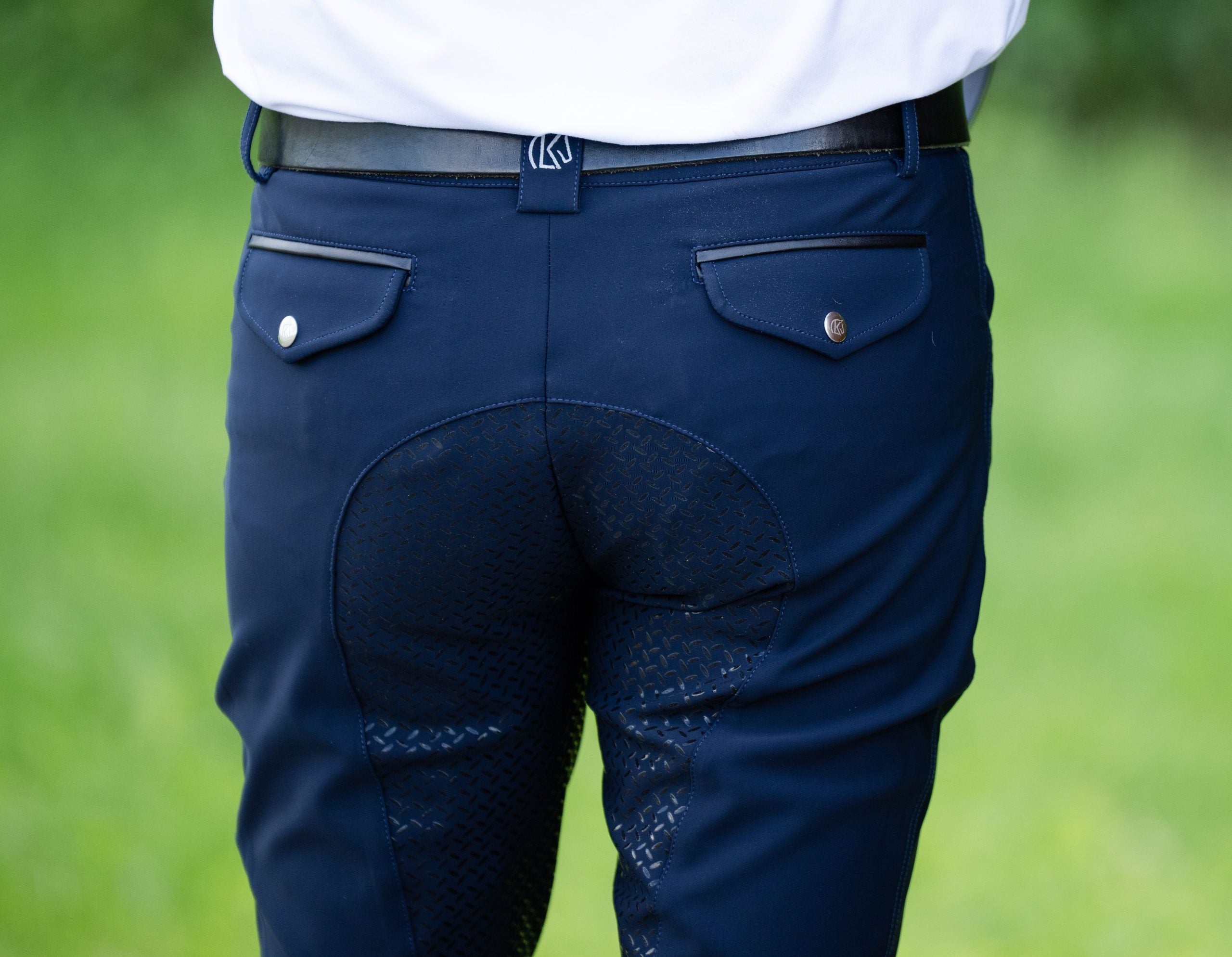 Close-up back view of a male model wearing the navy KL Select Men's Evan Full Seat Breeches while standing outside