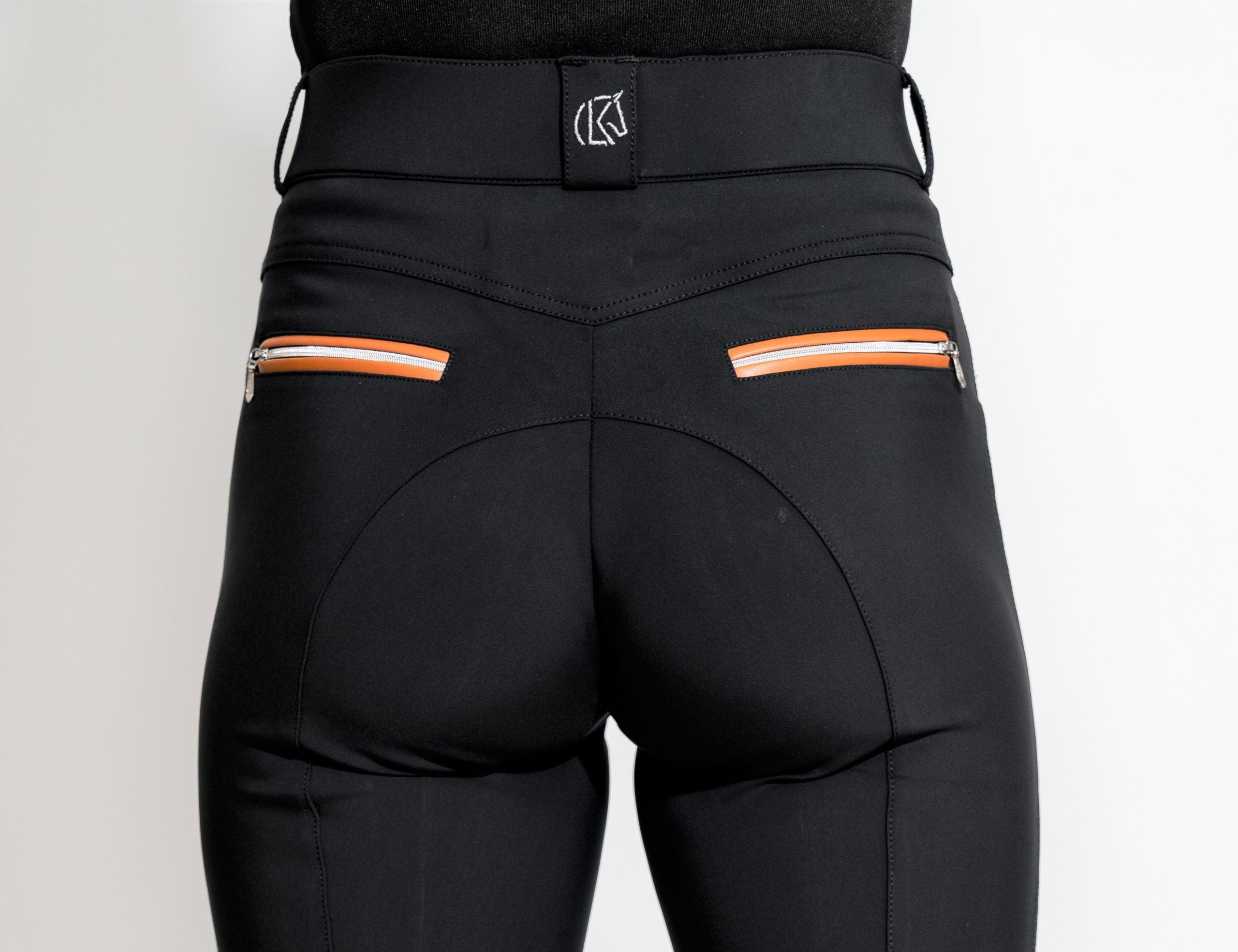 Close-up back view of a model wearing the black/cognac KL Select Gabrielle Knee Patch Breech on a plain background