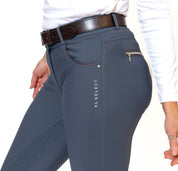 Close-up side view of a model wearing the slate blue KL Select Gabrielle Full Seat Breech on a white background