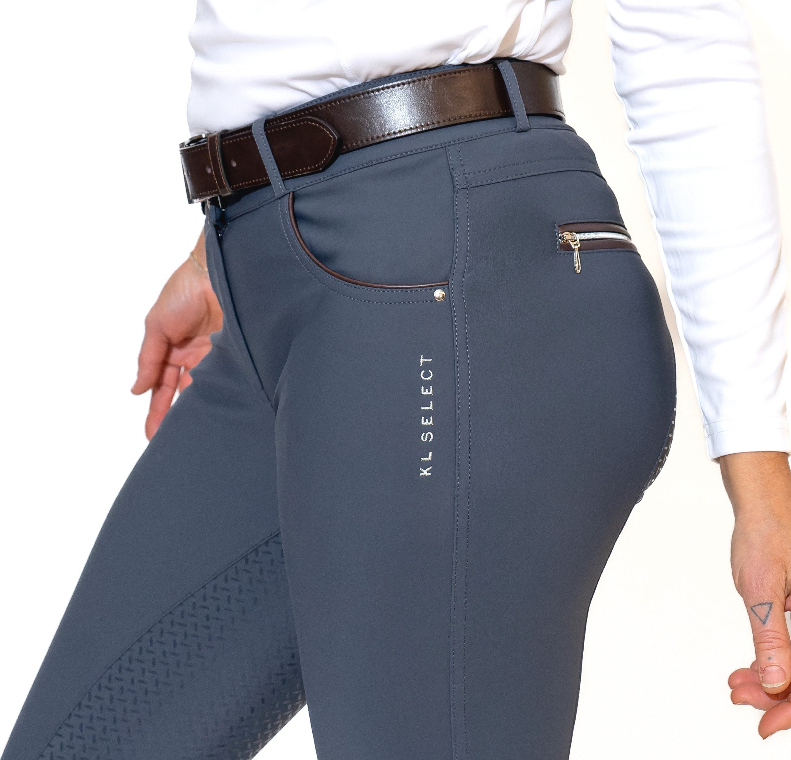Close-up side view of a model wearing the slate blue KL Select Gabrielle Full Seat Breech on a white background