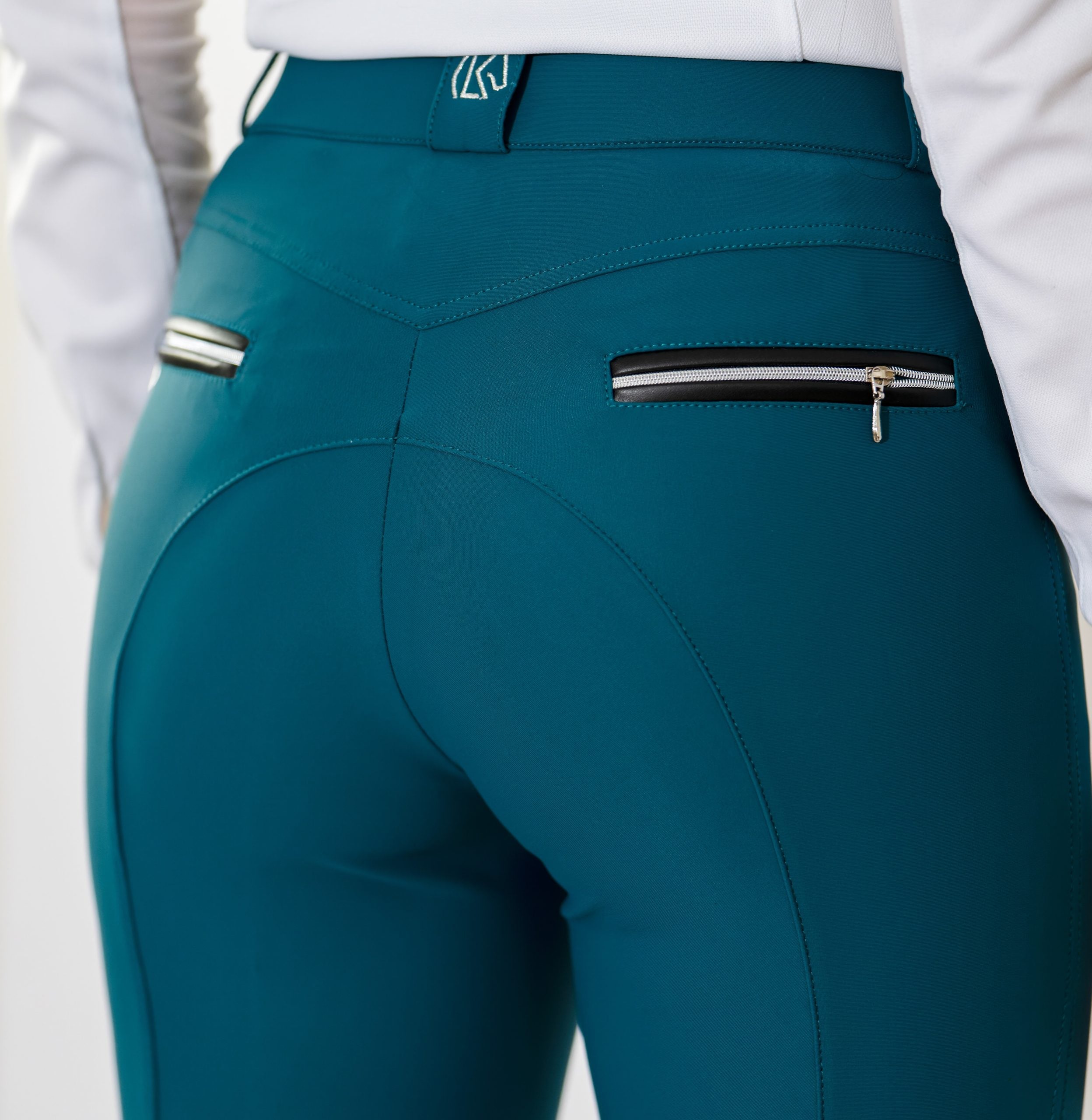 Close-up back view of a model wearing the teal KL Select Gabrielle Knee Patch Breech on a white background