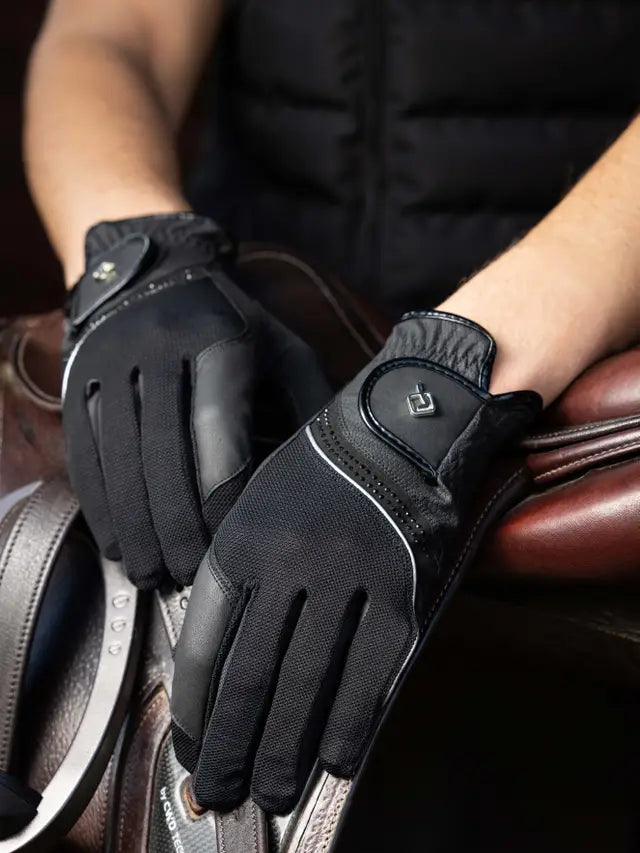 Person wearing black LeMieux Crystal Gloves with hands laid over english saddle