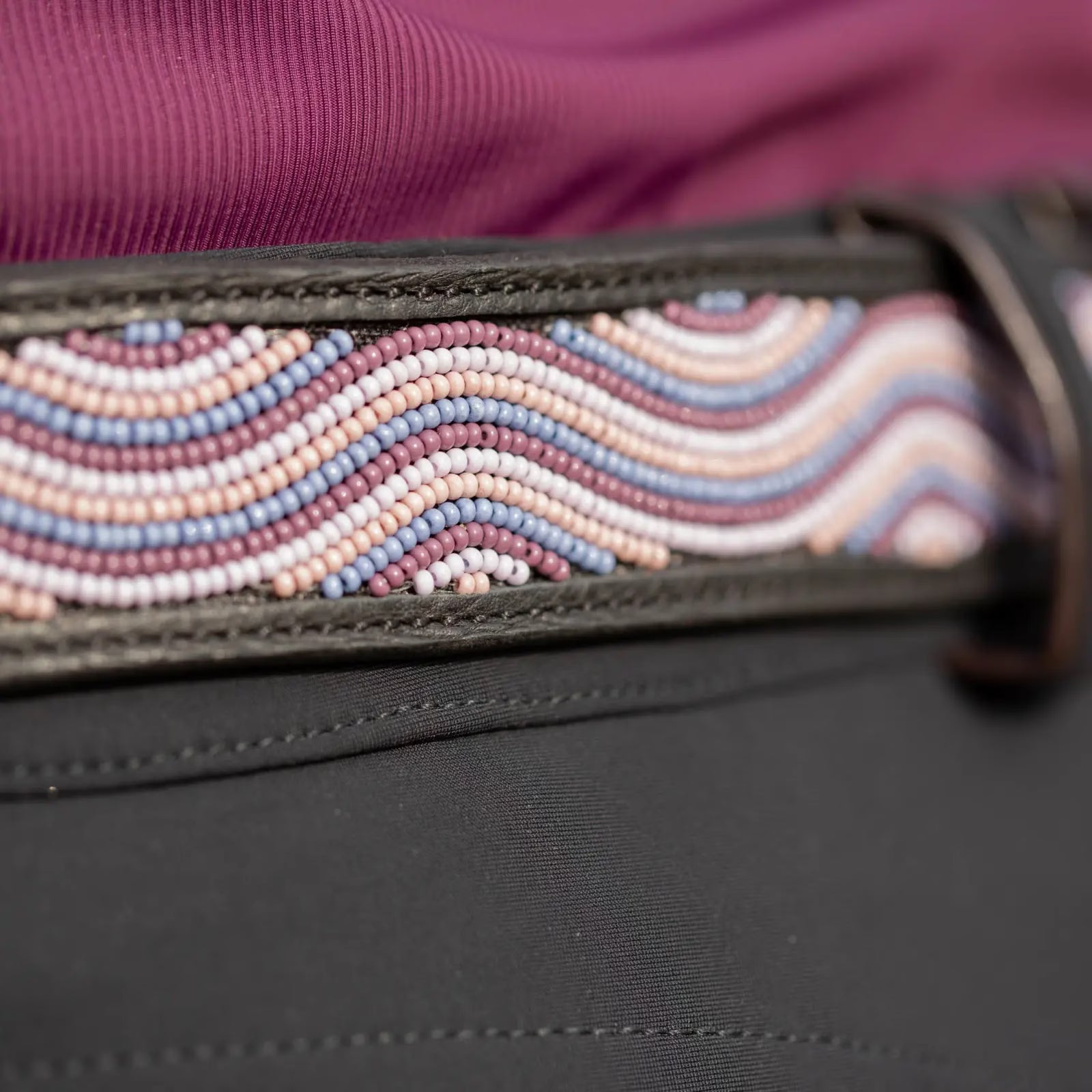 View of a black leather Equinavia Estelle Hand Beaded Belt with pink, purple, and tan beading on a black pair of breeches