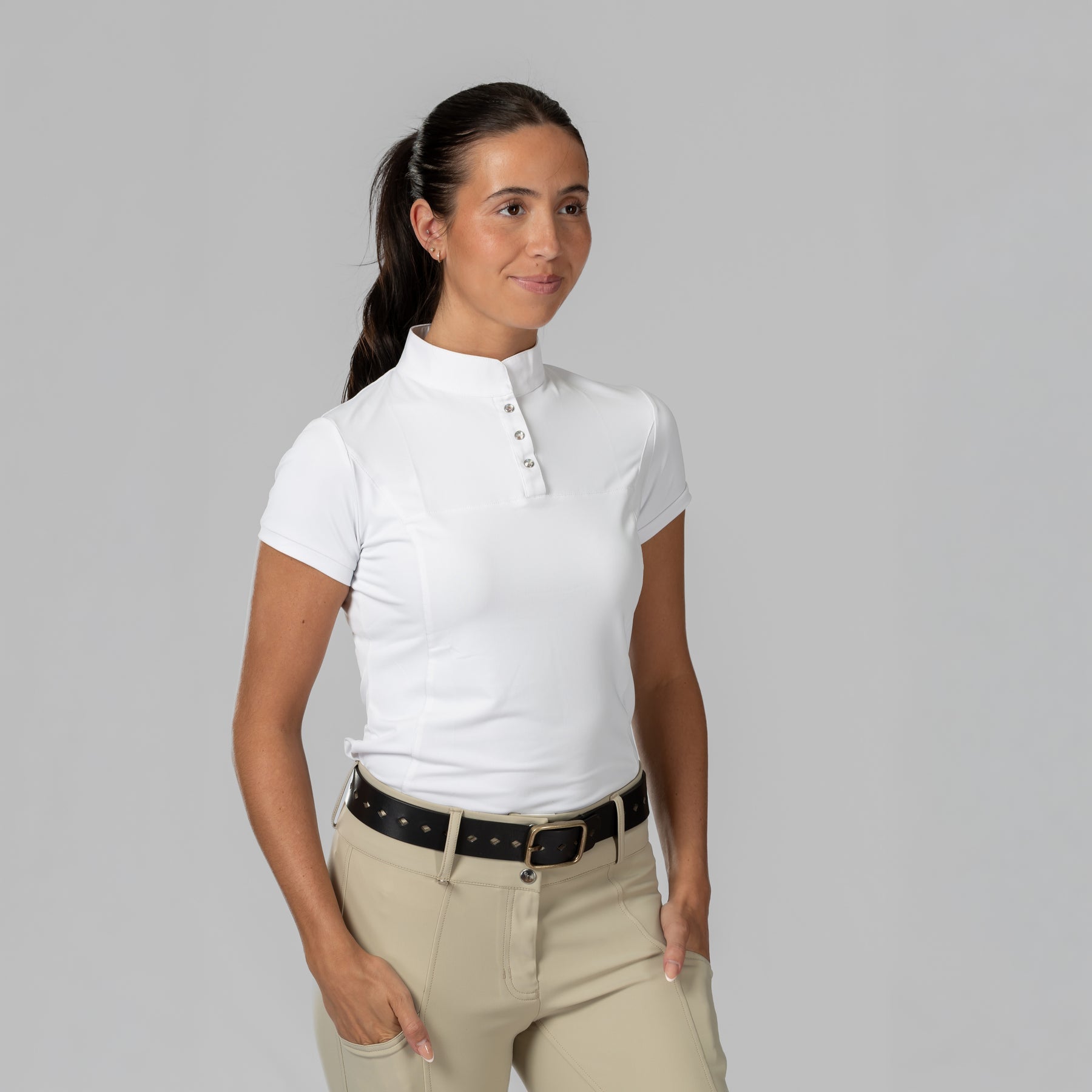 Front view of a female model wearing the white Horze Mina Short Sleeve Crystal Show Shirt on a plain background