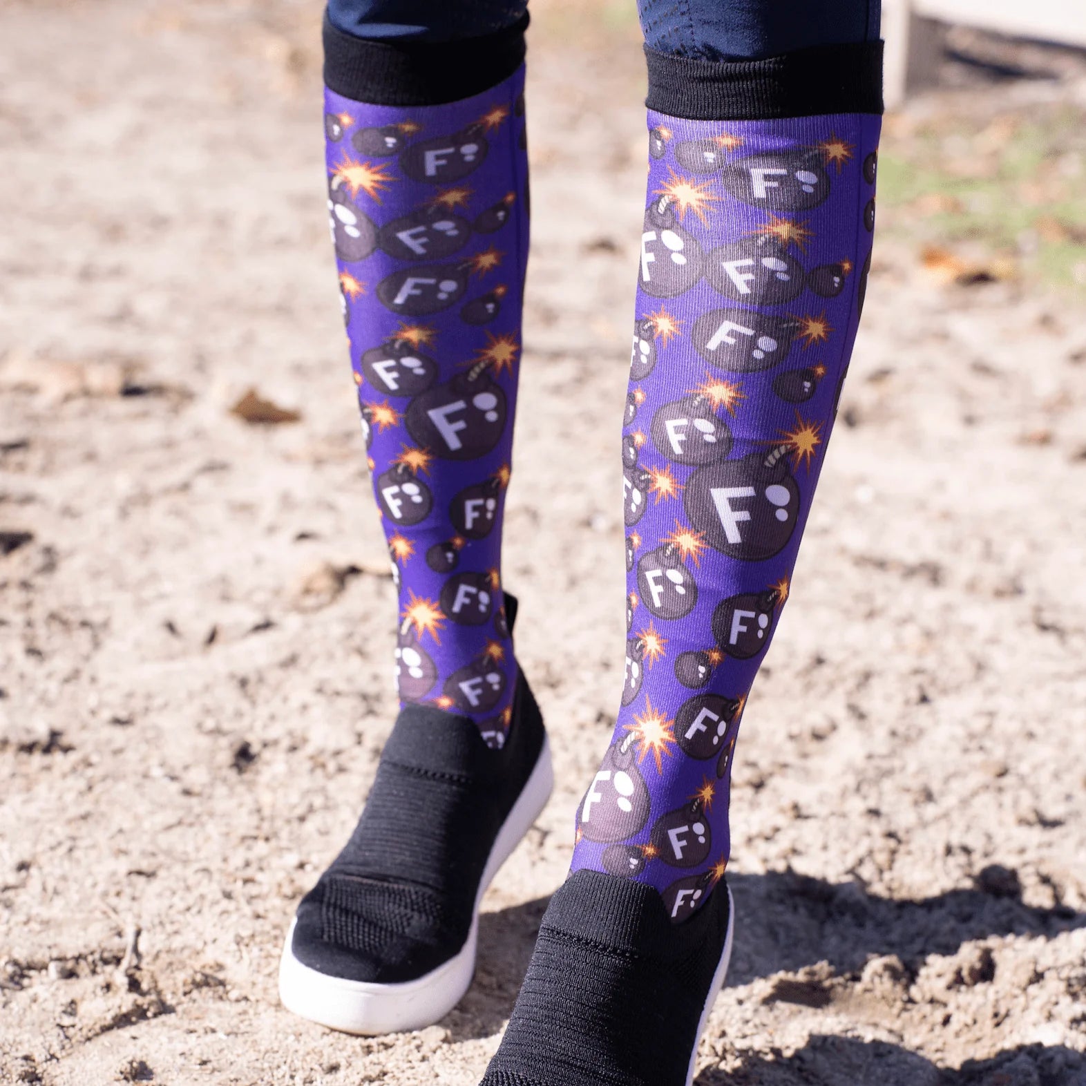 Front view of a model wearing the F Bomb Dreamers & Schemers Pair & A Spare Boot Socks while standing on arena footing