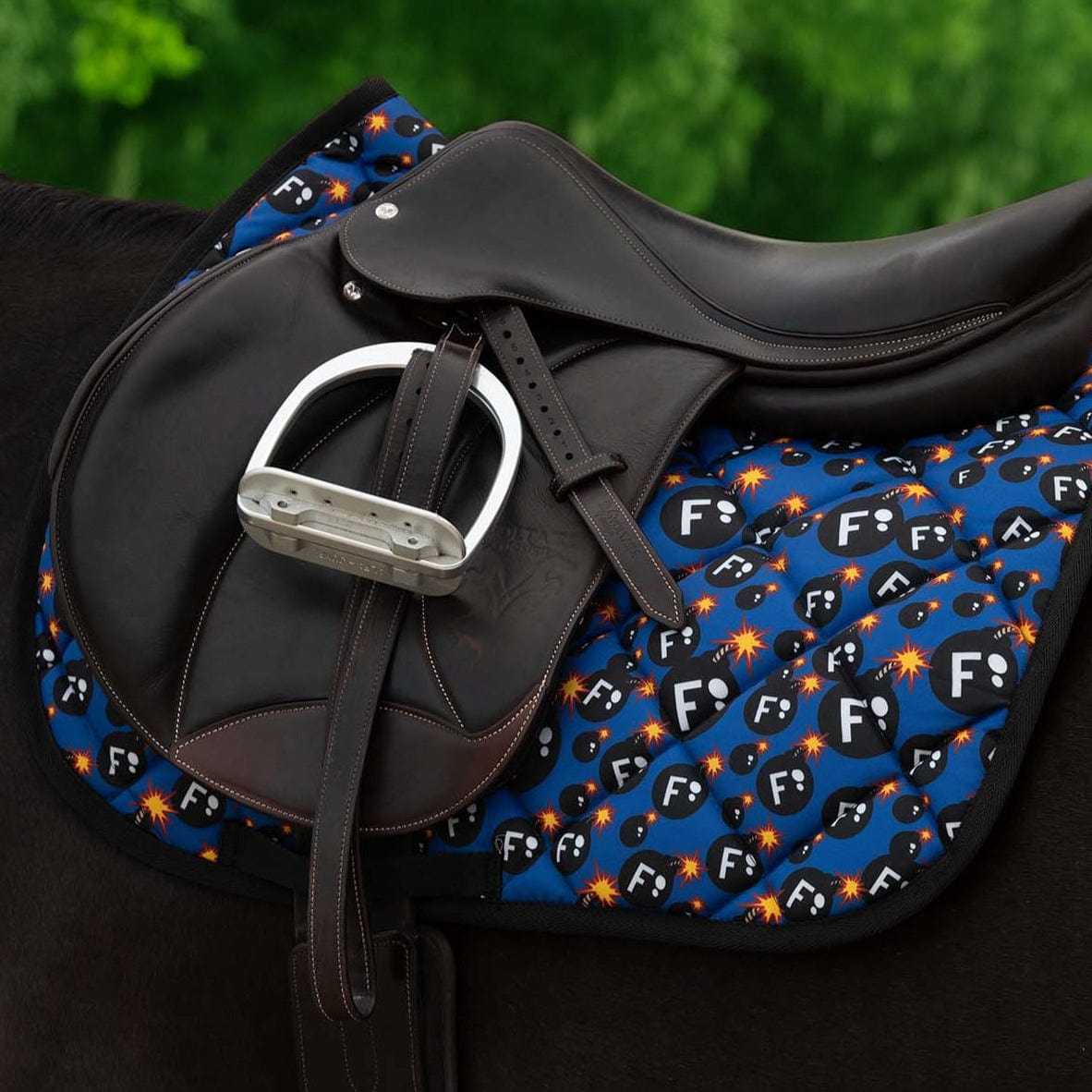 Side view of a black horse wearing the F Bomb Dreamers & Schemers Saddle Pad under a jump saddle