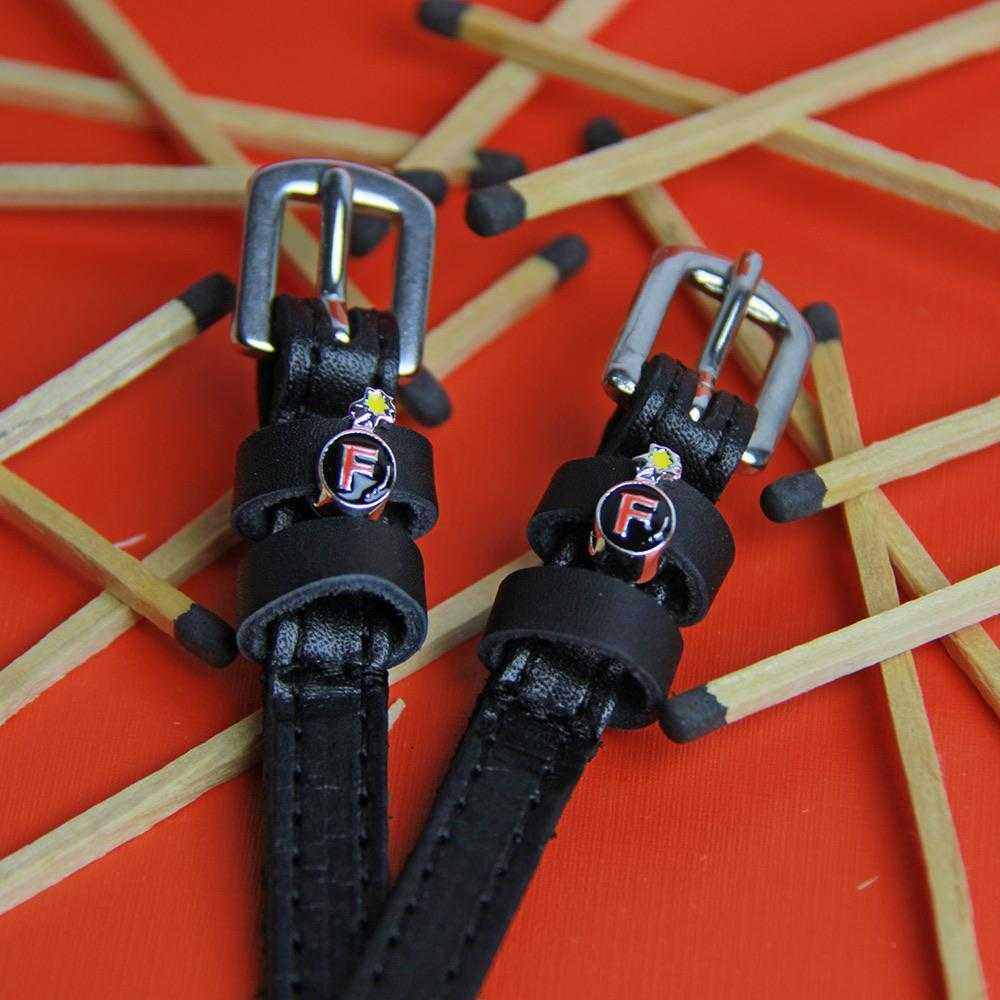 Close up view of the F Bomb Mane Jane Spur Straps on a red background covered in matchsticks
