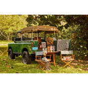 View of the Blue Stallion Farm Black & White Houndstooth Flannel Fleece Blanket in Leather Holder hung on the back of a green card parked in the grass