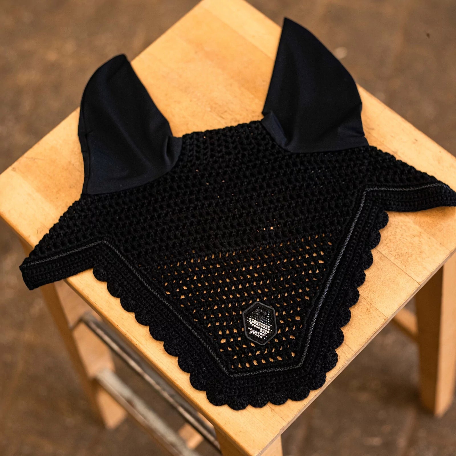Front view of the black swarovski Samshield Flyshield Fly Veil on a wood table