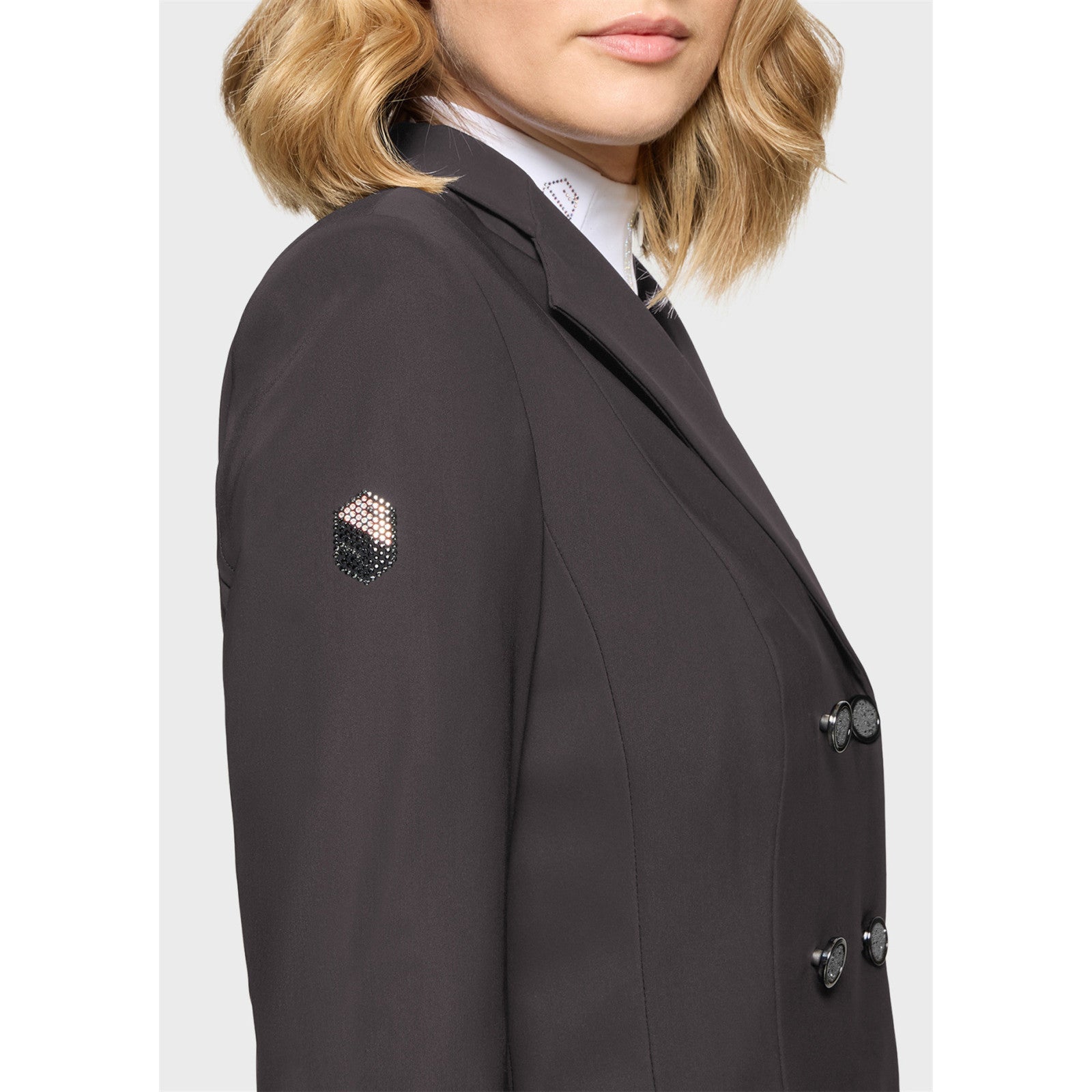 Close-up side view of a female model wearing the Truffle Samshield Frac Crystal Fabric Show Coat on a plain background