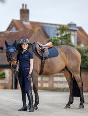 Rider standing with tacked up horse wearing LeMieux Acoustic Pro Fly Hood in navy outdoors