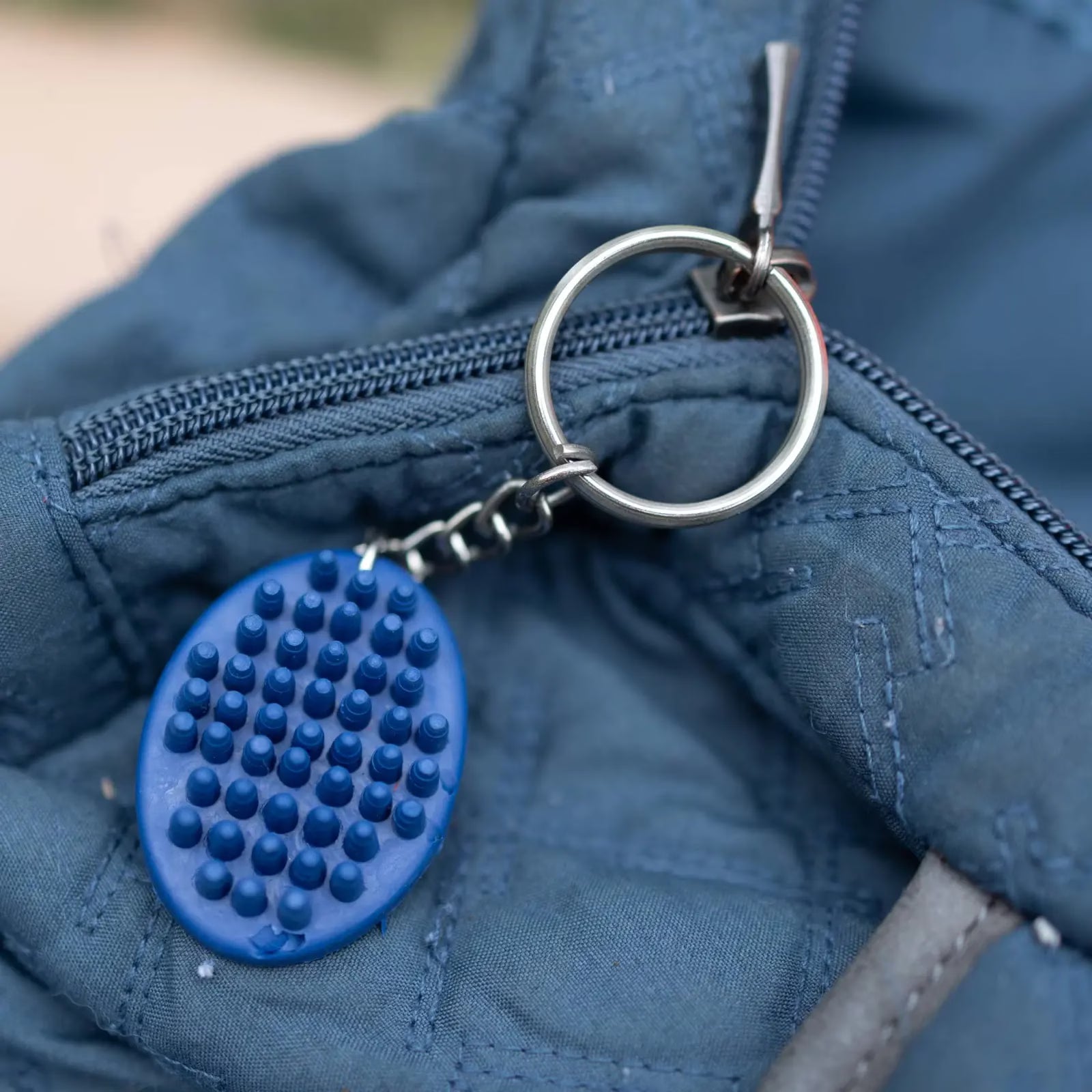 View of the blue Horze Brush Key Chain on a blue zipper