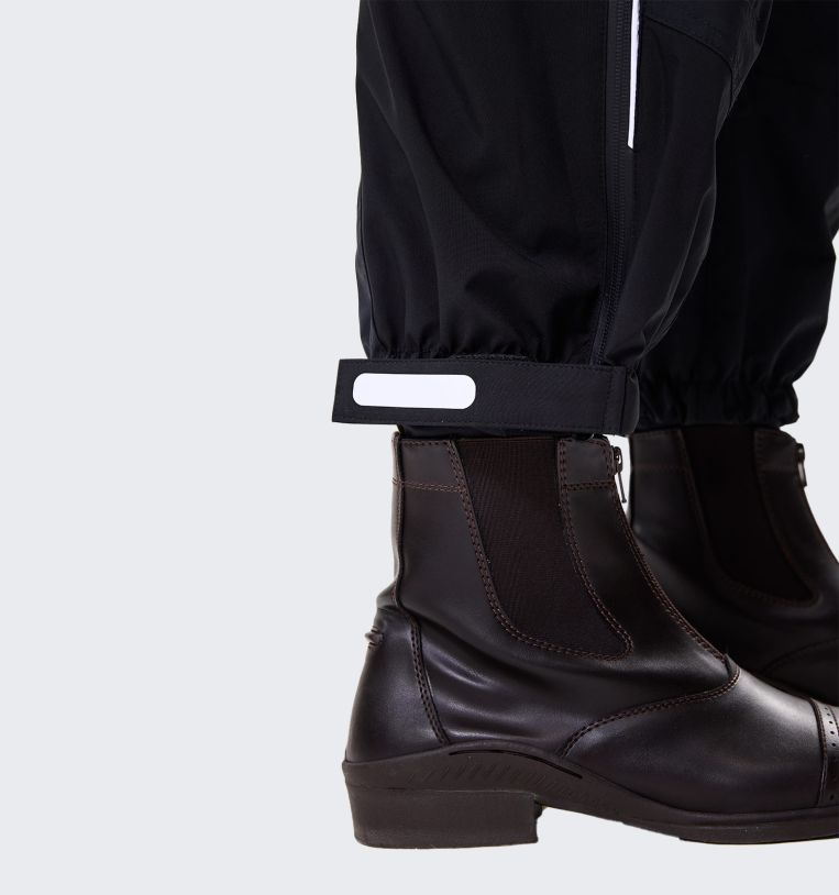 Close-up of Horseware H2O Trousers in black showing adjustable ankle strap above paddock boot