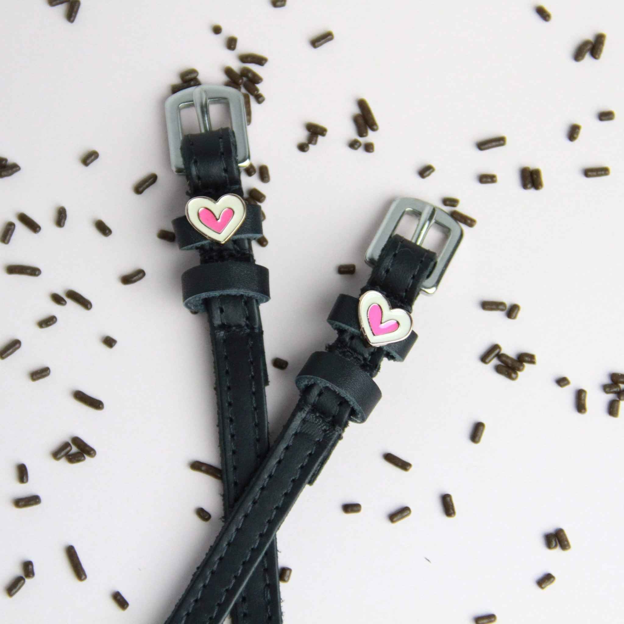 Front view 0f the Heart Smooshes Mane Jane Spur Straps on a plain background with scattered chocolate sprinkles 