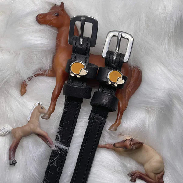 Front view of the Hedgehog Mane Jane Spur Straps on a white fluffy background with toy horses