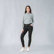 Full body front view of a model wearing the Equinavia Kari Womens Long Sleeve Sun Shirt with NordicAir Tech in gray, black breeches, and white sneakers on a gray background