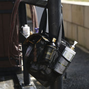 View of a Hairy Pony Horse Wash Bay Bag hanging on a railing and filled with bathing supplies