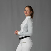 Side view of a model wearing the Equinavia Sara Womens Perforated Long Sleeved Show Shirt in light blue and white on a gray background