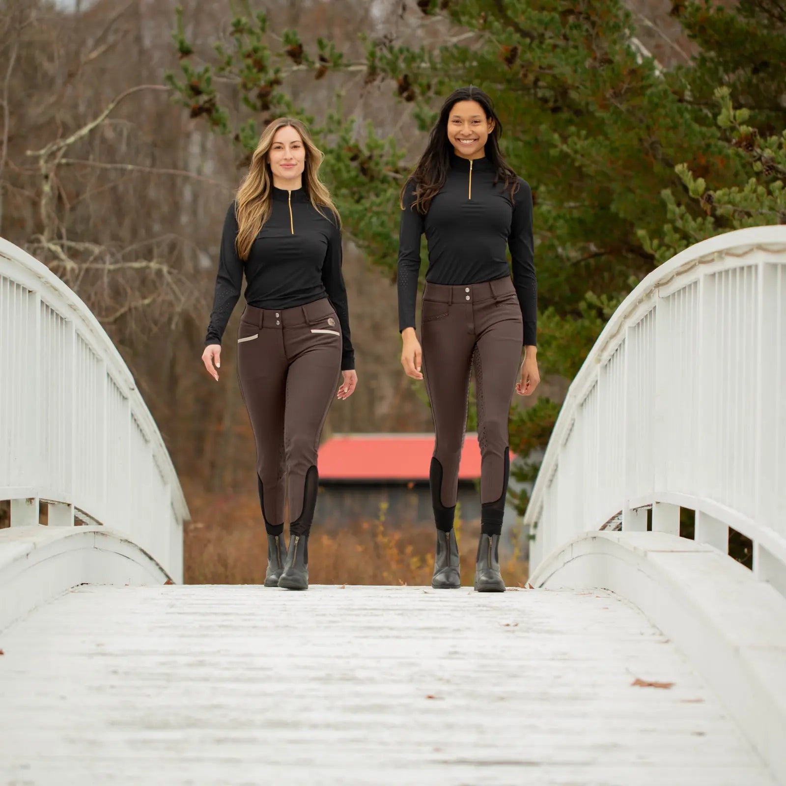 Front view of 2 female models wearing black tops and brown Equinavia Victoria Full Seat Breeches while walking over a bridge