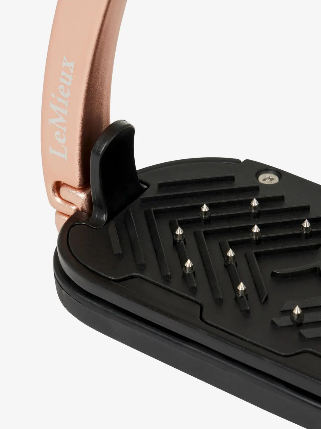 Close-up view of the tread on a rose gold LeMieux Vector Control Stirrup on a plain background