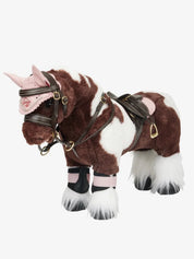 Side view of a paint toy pony wearing the brown LeMieux Toy Pony Saddle and Girth and pink accessories on a white background