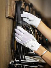 Person wearing white LeMieux Crystal Gloves while adjusting a bridle on a bridle rack