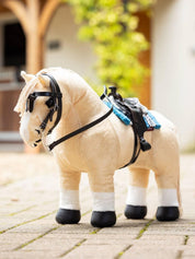 Side view of a palomino toy pony wearing the black LeMieux Toy Pony Western Bridle while standing on a brick path