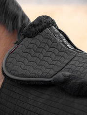 Close-up view of the black LeMieux Merino+ ProSorb 2 Pocket Half Pad over a black saddle pad worn by a bay horse