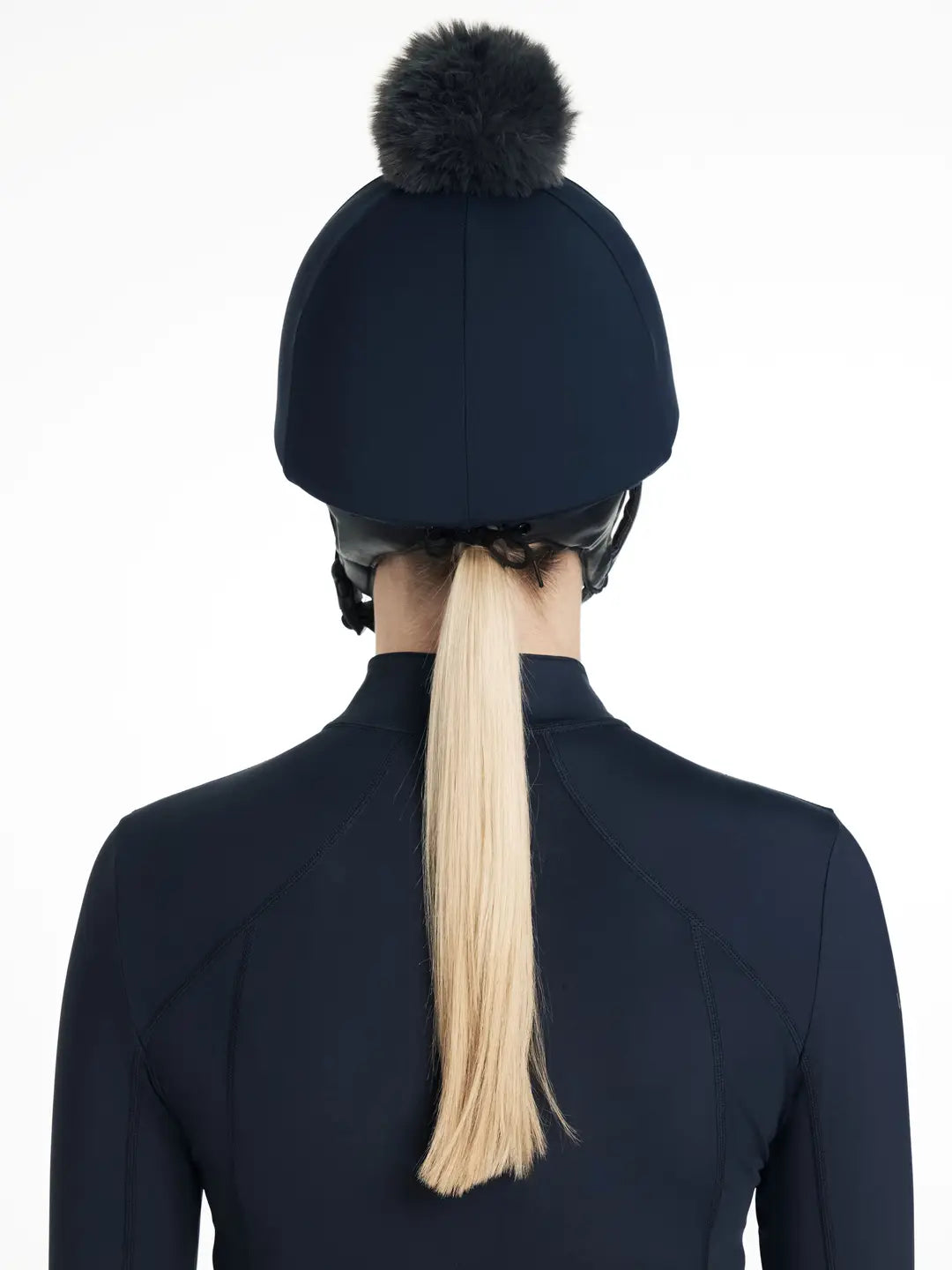 Back view of a female model wearing the navy LeMieux Classique Pom Hat Silk on a plain background