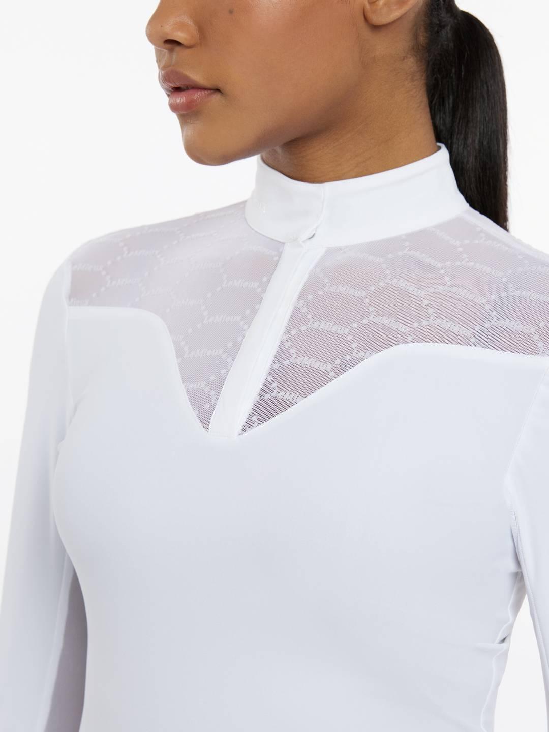 Close-up front view of a female model wearing the white LeMieux Emily Long Sleeve Show Shirt on a plain background
