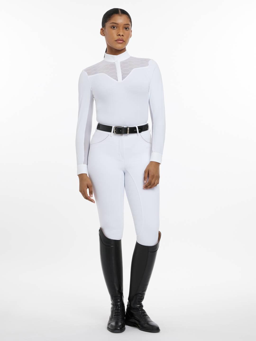 Full body front view of a female model wearing the white LeMieux Emily Long Sleeve Show Shirt and white breeches on a plain background