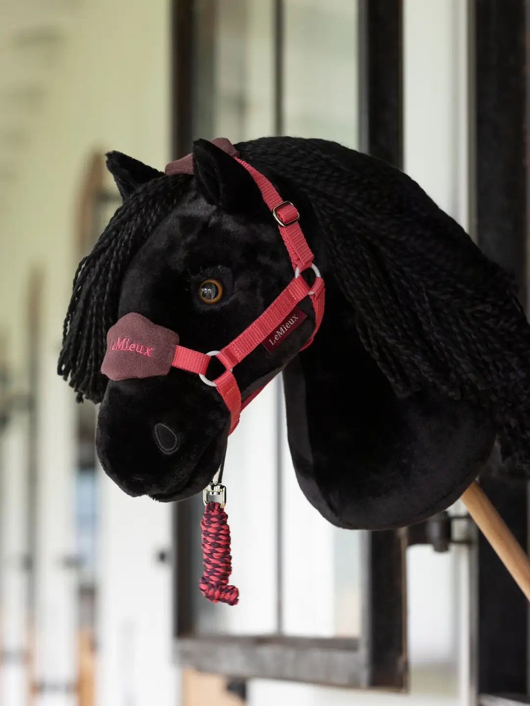 Side view of the Spike black LeMieux Hobby Horse in a barn aisle