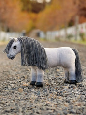 A gray stuffed animal horse on a gravel path