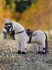 A gray stuffed animal horse with tack on a gravel path
