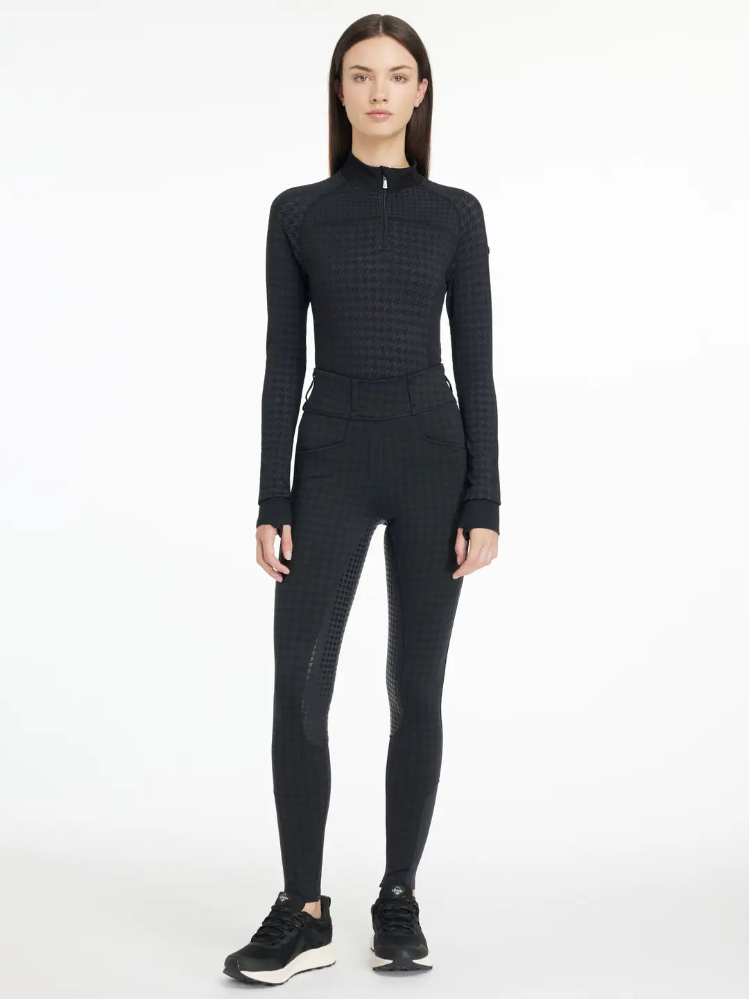 Full body front view of a model wearing the LeMieux Aspen Houndstooth Gigi Bregging, matching top, and black tennis shoes on a plain background