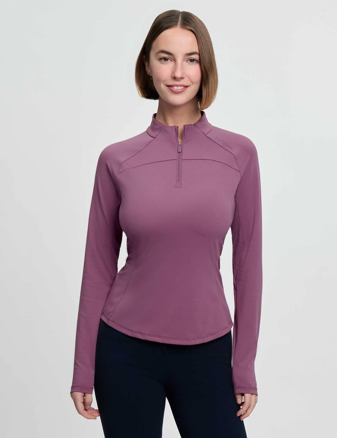 Front view of a female model wearing the purple LeMieux Airflow Long Sleeve Base Layer on a plain background