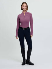 Full body front view of a female model wearing the purple LeMieux Airflow Long Sleeve Base Layer and dark colored breeches on a plain background