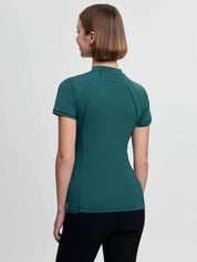 Back view of a female model wearing the green LeMieux Lisa Mesh Short Sleeve Base Layer on a plain background