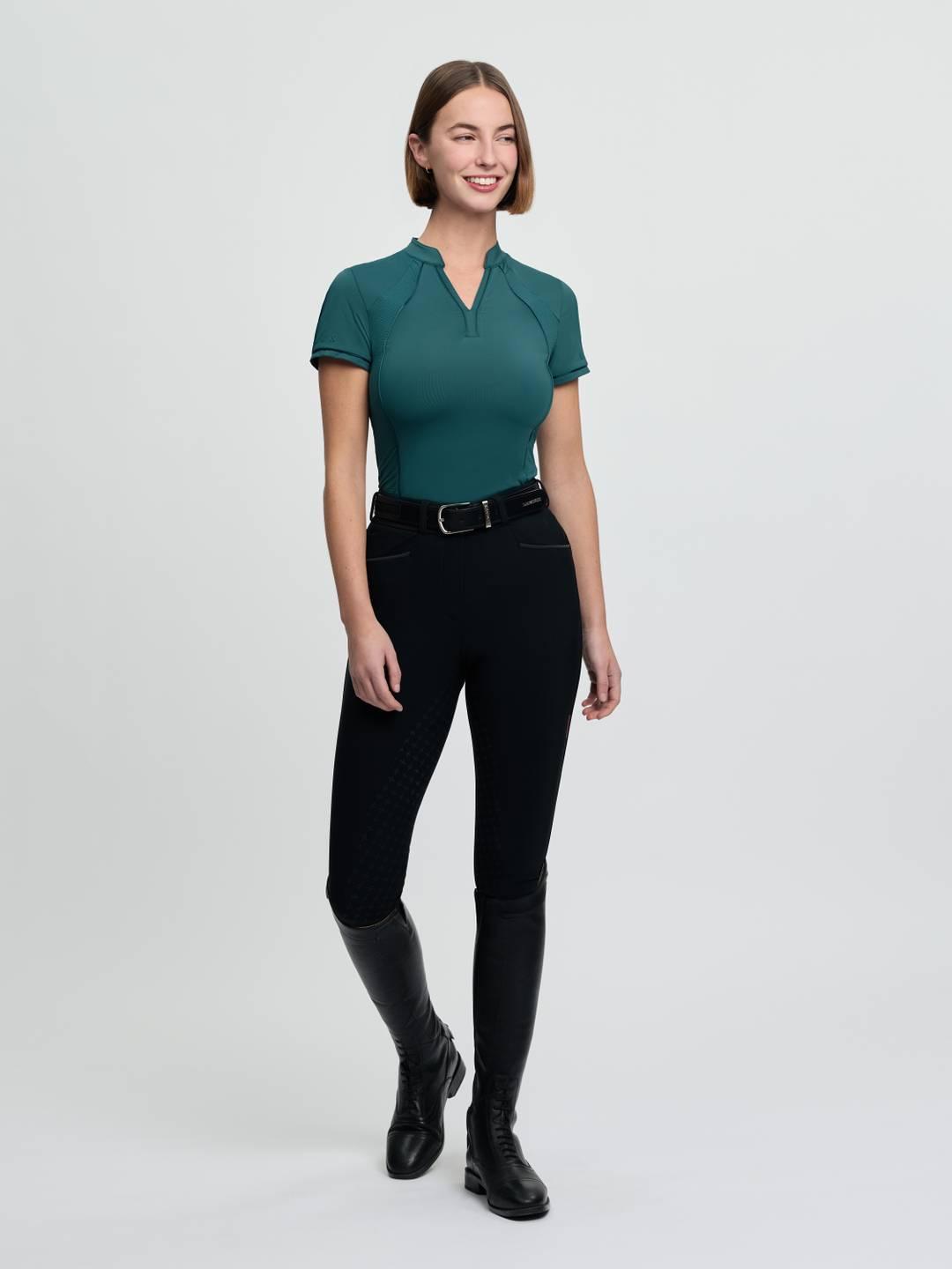 Full body front view of a female model wearing the green LeMieux Lisa Mesh Short Sleeve Base Layer on a plain background