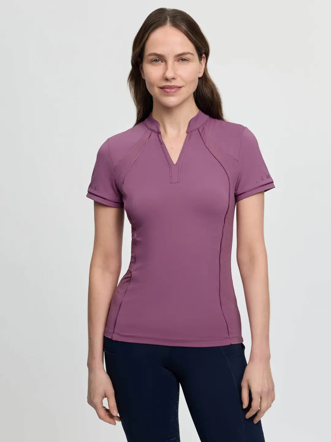 Front view of a female model wearing the purple LeMieux Lisa Mesh Short Sleeve Base Layer on a plain background
