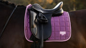 Close-up of purple quilted dressage saddle pad under a black saddle