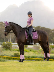 Rider on a horse wearing a purple dressage saddle pad with matching accessories