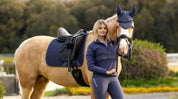 Woman standing outside next to a palomino horse wearing the LeMieux Air-Tek Mesh Dressage Square under a black saddle