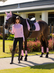 Woman standing next to a horse tacked up in LeMieux Fondant saddle pad and accessories