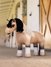 A buckskin paint stuffed animal horse standing in a barn aisle